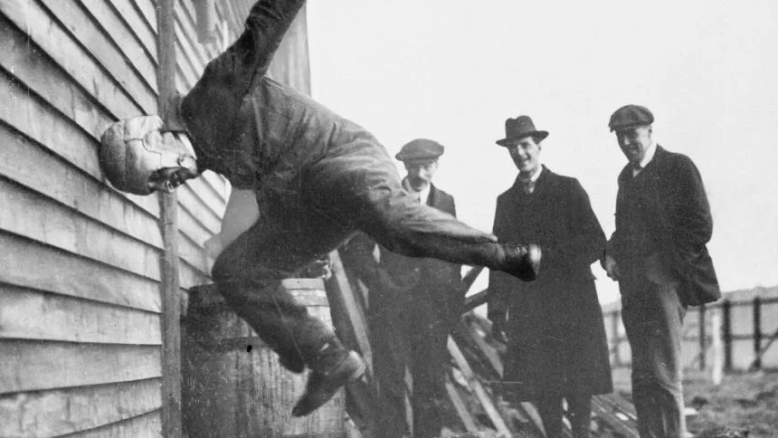 The picture is from the year 1912. Mr Warren was a tinkerer. He introduced his latest invention to experienced pilots: a protective helmet that 
