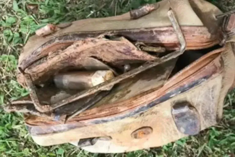 Un bambino pesca dall'acqua un vecchio borsellino e agisce in fretta quando ne sbircia l'interno