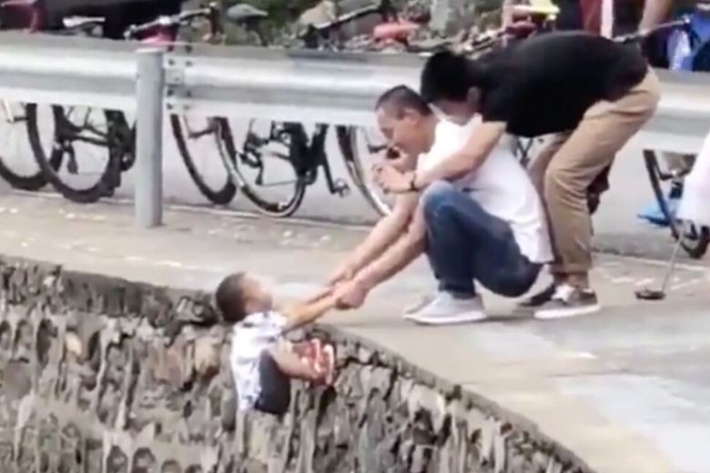 Familieleden laten jongetje aan rand klif bungelen voor het perfecte kiekje
